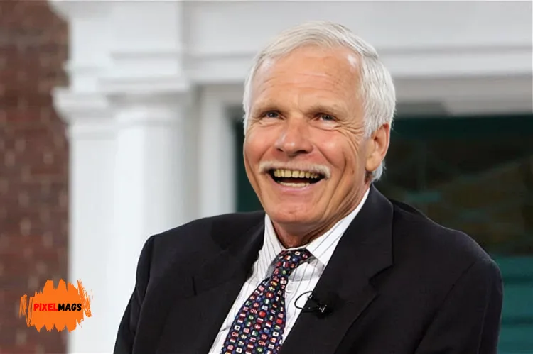 Ted Turner smiling warmly while wearing a small microphone sited in chair.