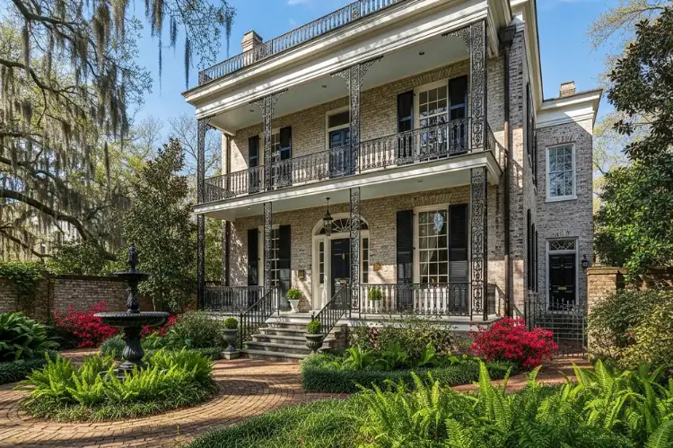 Regency-style historic home with iron balcony and brick courtyard