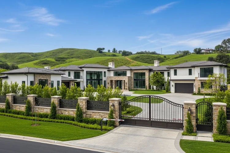 A massive gated estate in Hidden Hills surrounded by rolling green hills, privacy fences, modern mansion architecture.