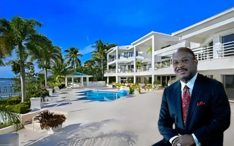 Willie Gary posing in front of his luxurious beachfront mansion with a large pool and palm trees.