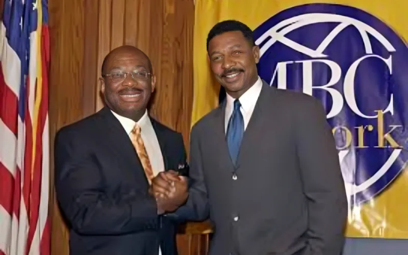willie gary and men in suits smiling and shaking hands at a formal event with a TBC Network banner in the background.