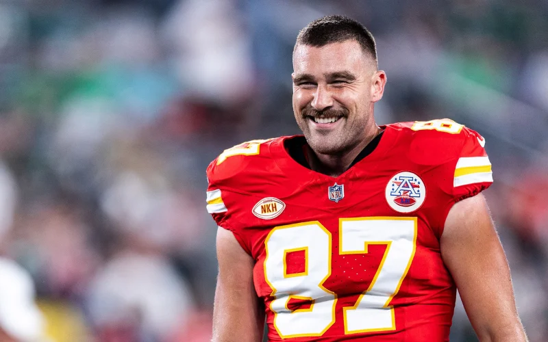 Kansas City Chiefs tight end Travis Kelce smiling in his red number 87 jersey after a game.